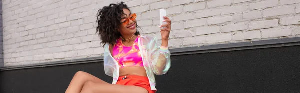 Uśmiechnięta Afroamerykanka Okularach Przeciwsłonecznych Pomocą Smartfona Zewnątrz Baner — Zdjęcie stockowe