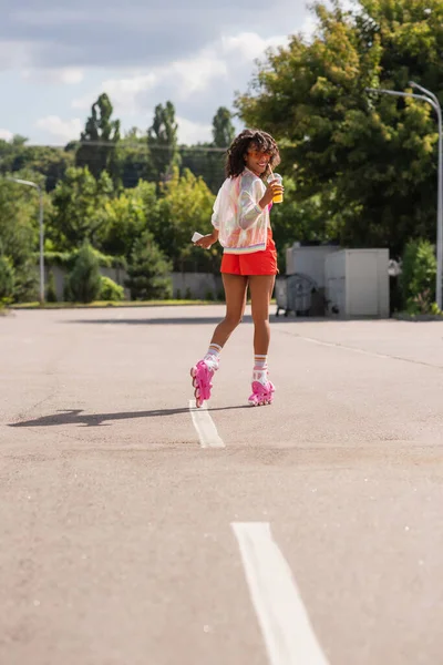 Longitud Completa Sonriente Mujer Afroamericana Patinando Patines Ruedas Mientras Sostiene — Foto de Stock