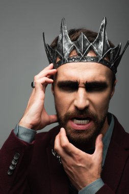 Vampir krallığındaki kızgın adam. Cadılar bayramı tacı. Yüze dokunuyor ve gri renkte sırıtıyor.