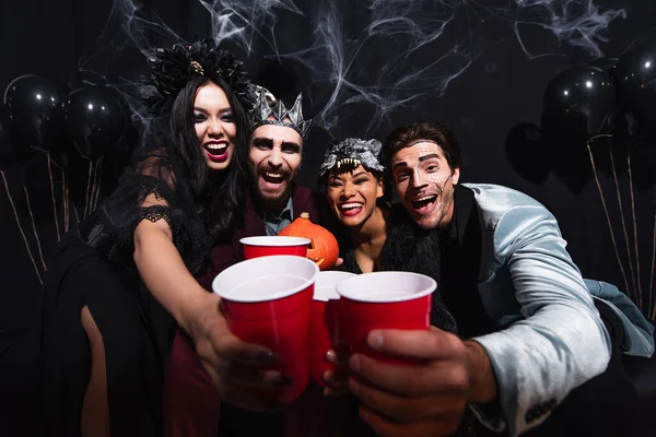 Amigos Multiculturais Animado Trajes Halloween Segurando Copos Plástico Enquanto Olha — Fotografia de Stock