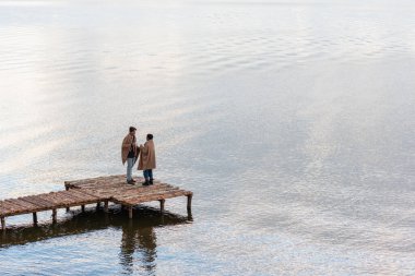 İskelede konuşurken ellerinde fincanlarla çok ırklı bir çift. 