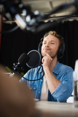 Düşünceli ve genç radyo sunucusu kulaklıklarla başka tarafa bakıyor.