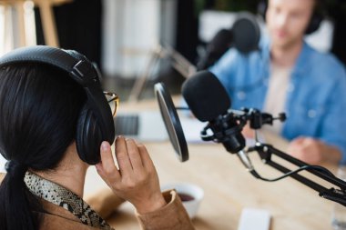 Gözlüklü radyo sunucusu. Kulaklığı bulanık meslektaşının yanında ayarlıyor. 