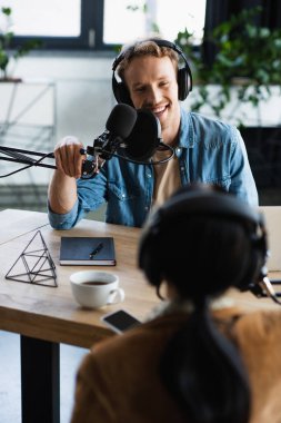 pozitif radyo sunucusu mikrofonla konuşuyor ve podcast sırasında bulanık meslektaşına bakıyor