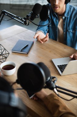 Podcast sırasında mikrofonla konuşan radyo sunucularının kırpılmış görüntüsü