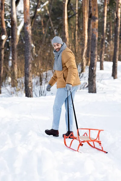 冬の公園でそりを引く暖かい服の笑顔の男 — ストック写真