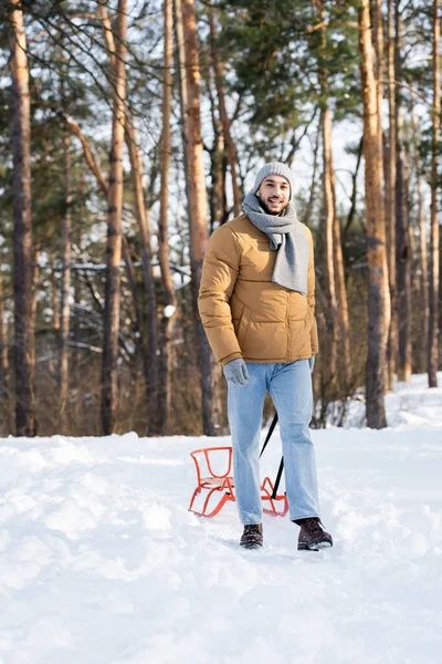 Uomo Felice Guardando Fotocamera Vicino Slitta Sulla Neve Nel Parco — Foto Stock