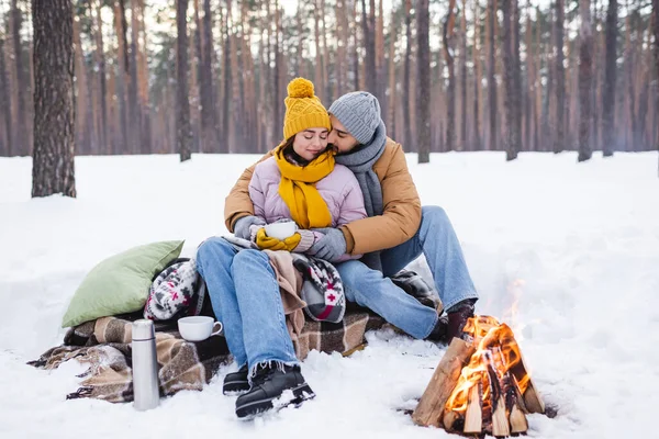 Homem Beijando Namorada Com Copo Perto Cobertores Fogueira Parque Inverno — Fotografia de Stock