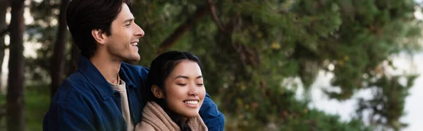 笑着站在亚洲女朋友身边 闭着眼睛 高举横幅 — 图库照片