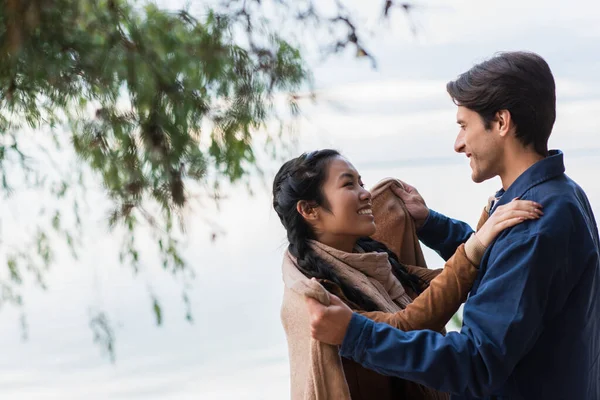 Cheerful Man Covering Asian Girlfriend Blanket Lake — Stock Photo, Image