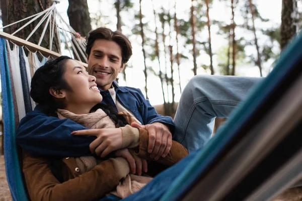一个快乐的男人在户外模糊的吊床上拥抱着亚洲女朋友 — 图库照片
