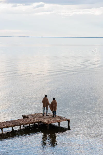 Vista Trasera Pareja Mantas Pie Muelle Madera Cerca Del Mar — Foto de Stock