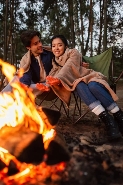 Cheerful Asian Woman Warming Hands Boyfriend Blurred Campfire — Stock Photo, Image