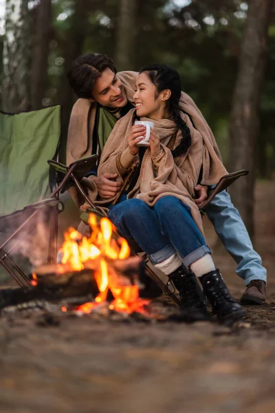 Smiling Man Blanket Standing Asian Girlfriend Cup Blurred Campfire Foreground — Stock Photo, Image