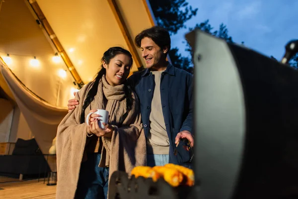 Smiling Asian Woman Holding Cup Boyfriend Grilling Corn Glamping House — Stock Photo, Image