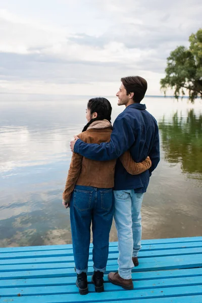 Sonriente Hombre Abrazando Asiático Novia Muelle Cerca Lago — Foto de Stock