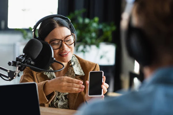 Glad Asiatisk Presentatör Glasögon Och Hörlurar Håller Smartphone Nära Suddig — Stockfoto