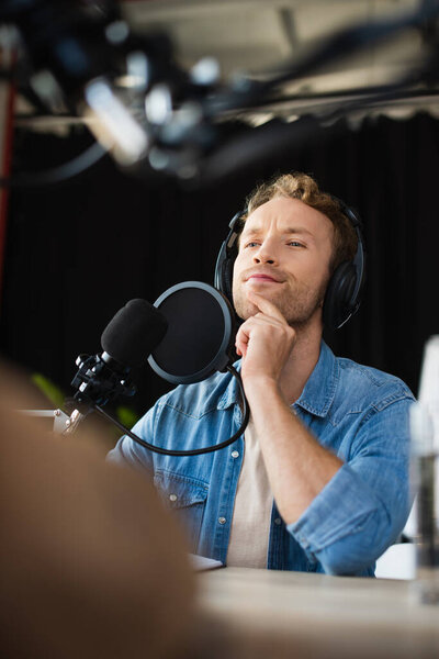 задумчивый и молодой радиоведущий в наушниках, отворачивающийся