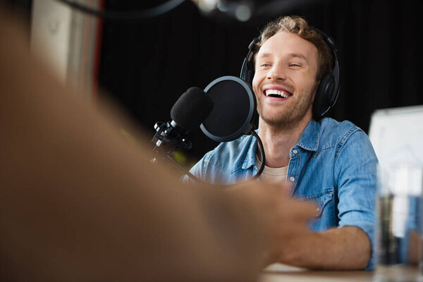 positive radio host in headphones laughing in studio 