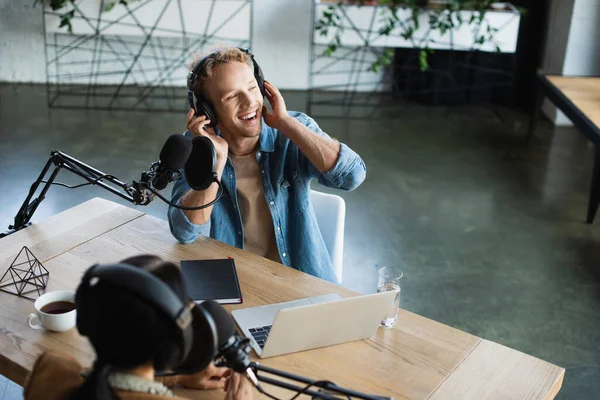 Szczęśliwy Gospodarz Radiowy Regulacja Słuchawek Pobliżu Mikrofonu Studio — Zdjęcie stockowe