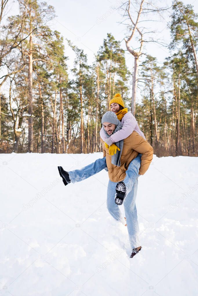 Young couple in winter outfit having fun in park with snow 