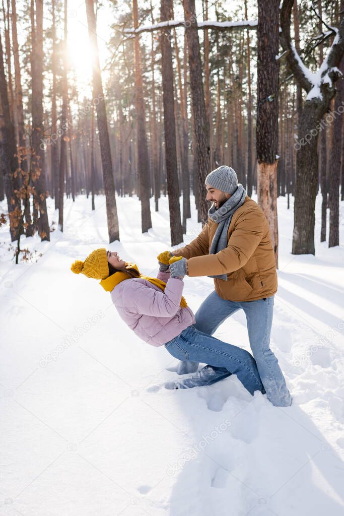 Side view of young couple having fun in snowy park 