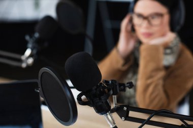 Bulanık Asyalı radyo sunucusunun yanında pop filtresi olan modern mikrofon
