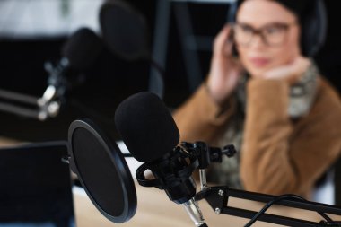 modern microphone with pop filter near blurred asian radio host clipart