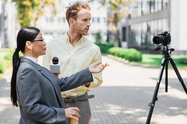 Reporter Holding Microfono Vicino Asiatico Businesswoman Indicando Digitale Fotocamera Treppiede — Foto Stock