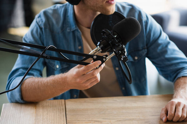 обрезанный вид влияния прикосновения ножниц руки рядом с микрофоном во время создания подкаста в студии 