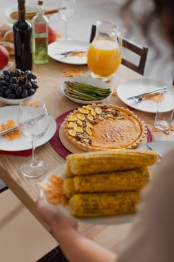 Cropped view of tasty thanksgiving dinner near blurred african american woman with corn  clipart