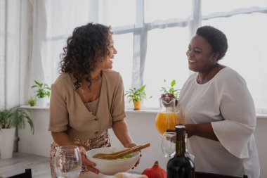 Neşeli Afrikalı Amerikalı anne ve kız Şükran Günü yemeğini evde servis ediyorlar. 