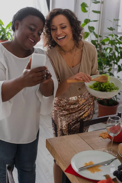 Mãe Afro Americana Mostrando Smartphone Filha Alegre Durante Jantar Ação — Fotografia de Stock