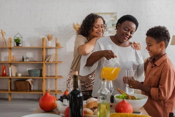 Glad Afrikansk Amerikansk Familj Häller Apelsinjuice Nära Thanksgiving Middag — Stockfoto