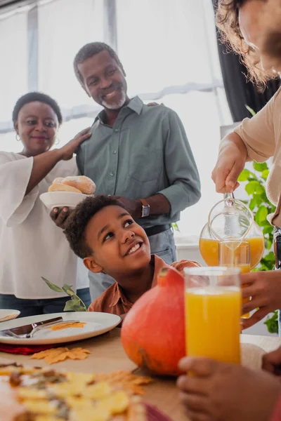 Niño Afroamericano Mirando Madre Con Jugo Naranja Cerca Los Abuelos — Foto de Stock