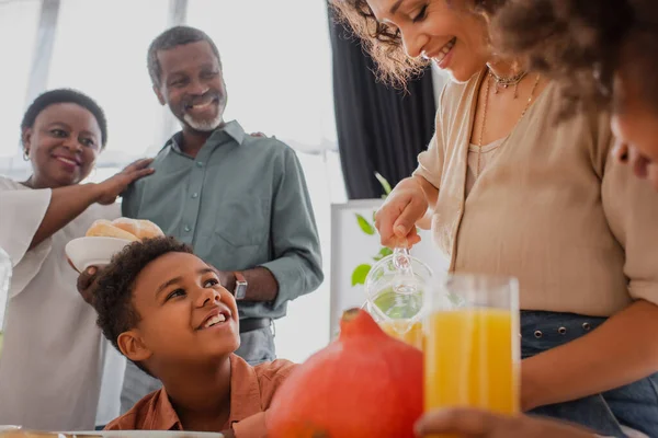 笑顔アフリカ系アメリカ人女性を保持オレンジジュース近く子供と親で自宅 — ストック写真