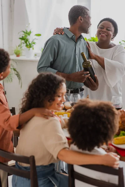 Avós Afro Americanos Com Vinho Perto Família Turva Jantar Ação — Fotografia de Stock