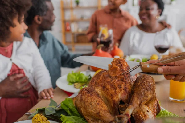 在模糊的非洲裔美国家庭附近切美味火鸡的女人 — 图库照片