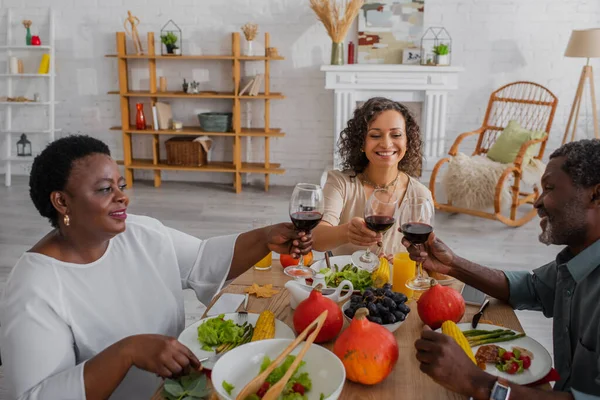 陽気なアフリカ系アメリカ人の両親と大人の娘感謝祭の夕食中にワインをクリック — ストック写真