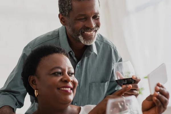 Africano Americano Mulher Apontando Para Smartphone Perto Marido Com Vinho — Fotografia de Stock