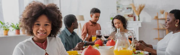 アフリカ系アメリカ人の女の子の笑顔近くに立っている家族と感謝祭の夕食 バナー — ストック写真