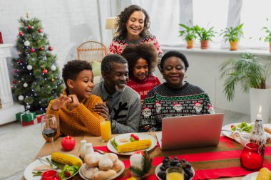 Mutlu Afro-Amerikan ailesi Noel yemeği sırasında görüntülü arama yapıyor.