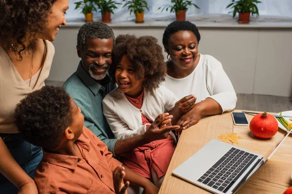 Glad Afrikansk Amerikansk Man Pekar Laptop Nära Familjen Tacksägelsedagen — Stockfoto