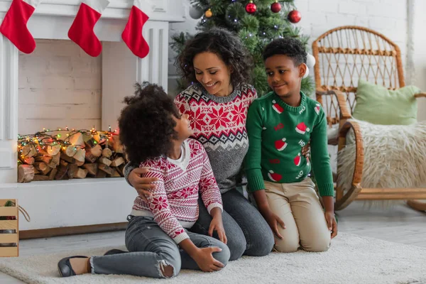 Mosolygós Afro Amerikai Ölelés Gyerekek Padlón Közelében Karácsonyfa Díszített Kandalló — Stock Fotó