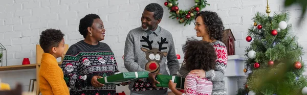快乐的非洲裔美国家庭 在圣诞树旁挂着礼品盒 挂着横幅 — 图库照片