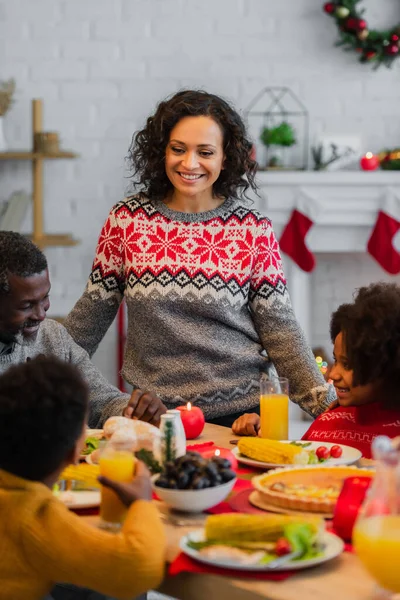 Mulher Americana Africana Sorrindo Perto Família Turva Tendo Jantar Natal — Fotografia de Stock
