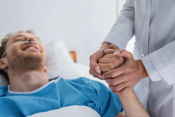 Lekarz Trzymający Rękę Niewyraźnego Uśmiechniętego Pacjenta Kaniulą Nosową — Zdjęcie stockowe