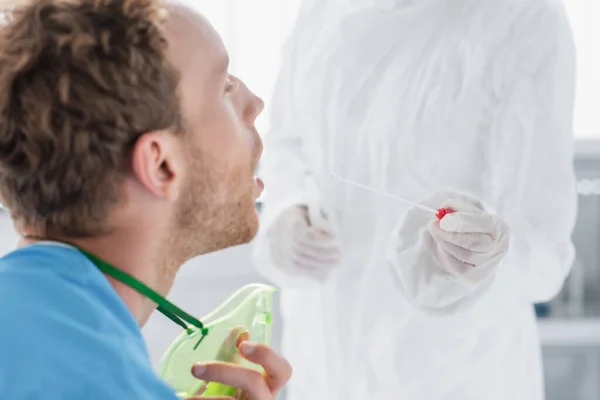 医生穿着危险物品服 带着乳胶手套 在张嘴的病人附近擦拭 — 图库照片