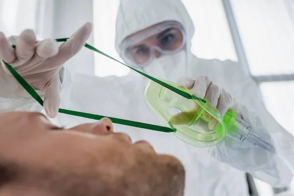 Doctor Hazmat Suit Latex Gloves Placing Oxygen Mask Blurred Patient — Stock Photo, Image