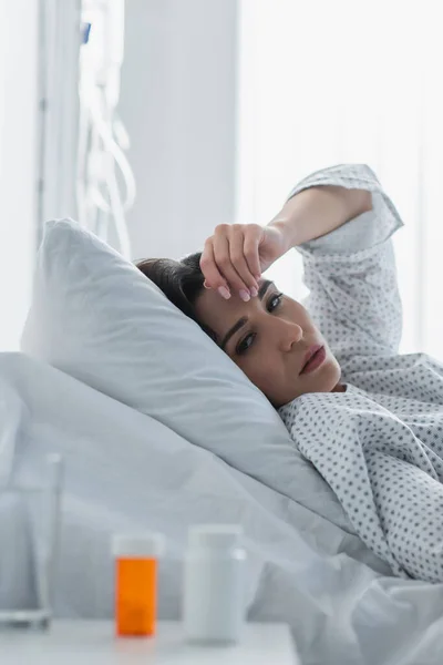 Zieke Vrouw Kijkt Naar Wazige Flessen Met Medicatie Het Ziekenhuis — Stockfoto